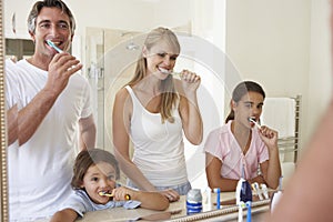 Family Brushing Teeth In Bathroom Mirror