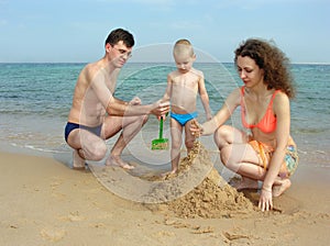 Family build sand castle on beach