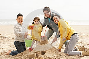 Family Building Sandcastle On Winter Beach