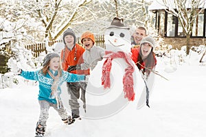 Familia el edificio muneco de nieve en el jardín 