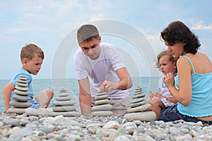 Family builds stone stacks on pebble beach