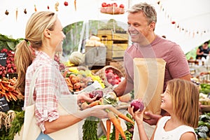 Family Buying Fresh Vegetables At Farmers Market Stall