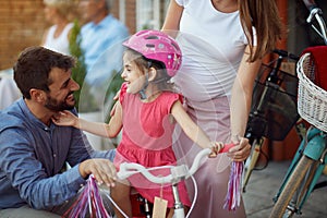 Family buying at happy girl bicycle helmet in bike shop
