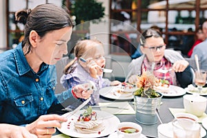 Family in a cafe - mother with daughters eating pavlova cake