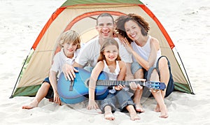 Family camping on beach playing a guitar