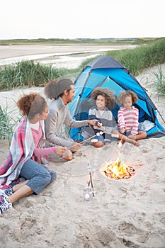 Family Camping On Beach And Toasting Marshmallows