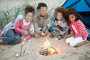 Family Camping On Beach And Toasting Marshmallows