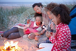 Family Camping On Beach And Toasting Marshmallows