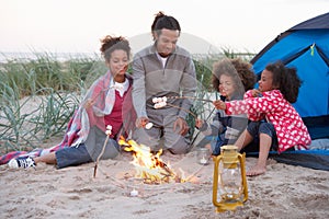 Family Camping On Beach And Toasting Marshmallows