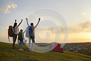 Family camping in nature. Parents and child with backpacks enjoying beautiful sunset at campground, copy space