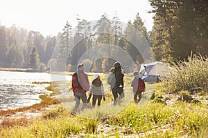 Family on a camping trip walking near a lake, back view