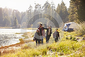 Family on a camping trip walking near a lake looking away