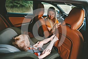 Family in car child sitting in safety seat and mother driver on road trip