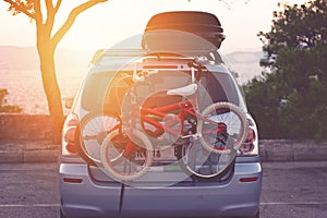 Family car with small kids bicycles rack, ready for travel, making a break on parking
