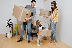 Family carry boxes to a stack, they are moving out from an old apartment