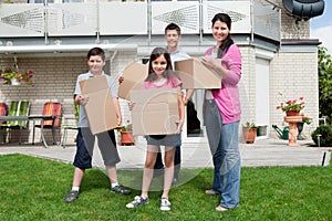 Family carrying boxes into new home