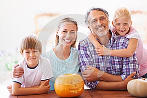 The family carving. Portrait of a family of four sitting with their jack-o-lantern at home.