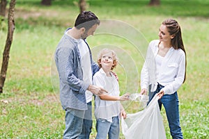 Family in casual clothes picking up garbage in plastic bag