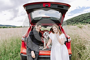 Family with a cat and a dog in nature on the background of his car