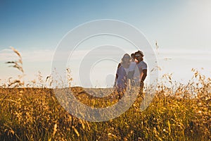 Family catching the sunset together in summer wheat field