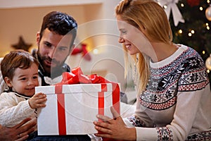 Family celebrating Christmas at home. father and mother give a c