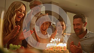 Family celebrating grandmother birthday on kitchen. Woman looking at cake