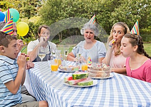 Family celebrating little girls birthday outside at picnic table