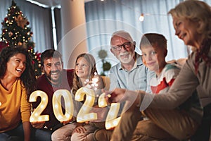 Family celebrating New Year, holding sparklers and illuminative numbers 2022