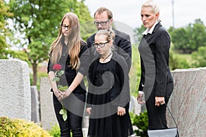 Family on cemetery mourning deceased relative photo