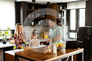 Family chatting and preparing food around a bustling kitchen counter filled with fresh ingredients and cooking utensils