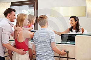 Family Checking In At Hotel Reception