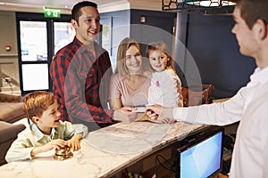 Family Checking In At Hotel Reception Desk