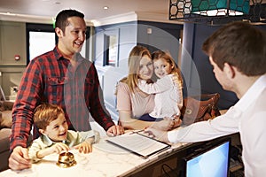 Family Checking In At Hotel Reception Desk photo