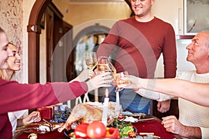 Family cheering and drinking on Thanksgiving on a blurred background. Family holiday gathering concept.