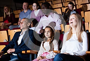 Family with child eating popcorn and watching a movie in the cinema