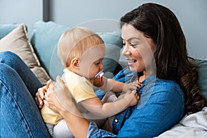 Family, child and motherhood concept - happy smiling young mother hugging little baby at home. Woman and her newborn boy or girl