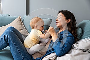 Family, child and motherhood concept - happy smiling young mother hugging little baby at home. Woman and her newborn boy or girl