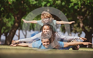 Family and child outdoors in spring nature. Fly concept, little boy is sitting pickaback while imitating the flight