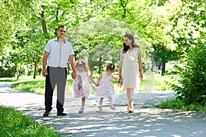 Family with child and pregnant woman walk in summer city park