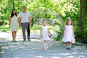 Family with child and pregnant woman walk in summer city park