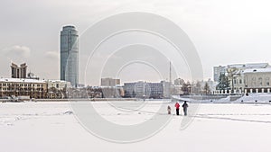 Family with child skiing on a cloudy winter day on the frozen city pond