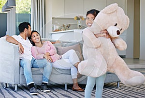 Family, child and teddy bear with hug in home, having fun and bonding with mother and father gift. Support, care and