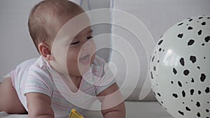 Family, childhood, infant concepts - Two children with newborn baby jumping with balloon on bed. Siblings little boy and