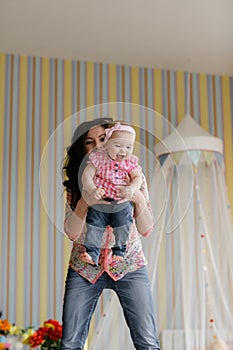 Family, childhood and parenthood concept - happy little baby learning to walk with mother help at home