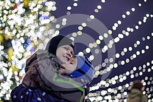 Family, childhood, season and people concept - happy in winter clothes over snowy city background