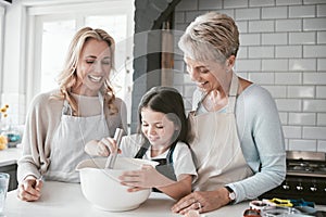 .Family, children and baking with a mother, grandmother and girl in the kitchen of their home together. Food, kids and