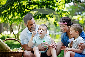 Family with children blow soap bubbles outdoors