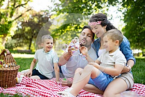 Family with children blow soap bubbles outdoors