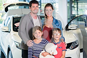 Family with children buying new car at auto dealership photo