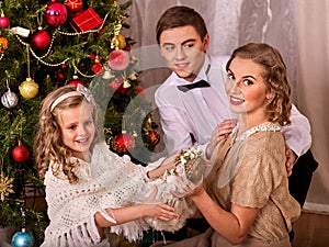 Family with children dressing Christmas tree.